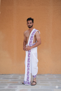 Man wearing a white dhoti with purple floral patterns 