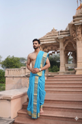 Man wearing a blue Dhoti standing on steps in a temple 