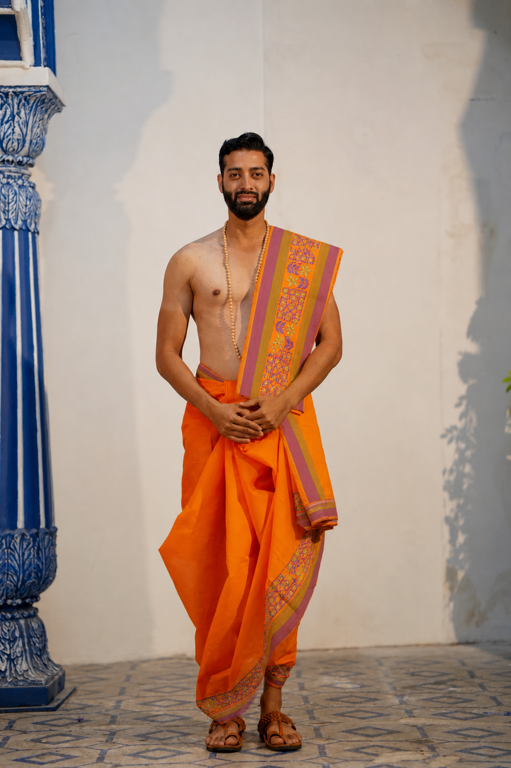 Man wearing a embroidery geomatric & floral border orange cotton dhoti with matching khes