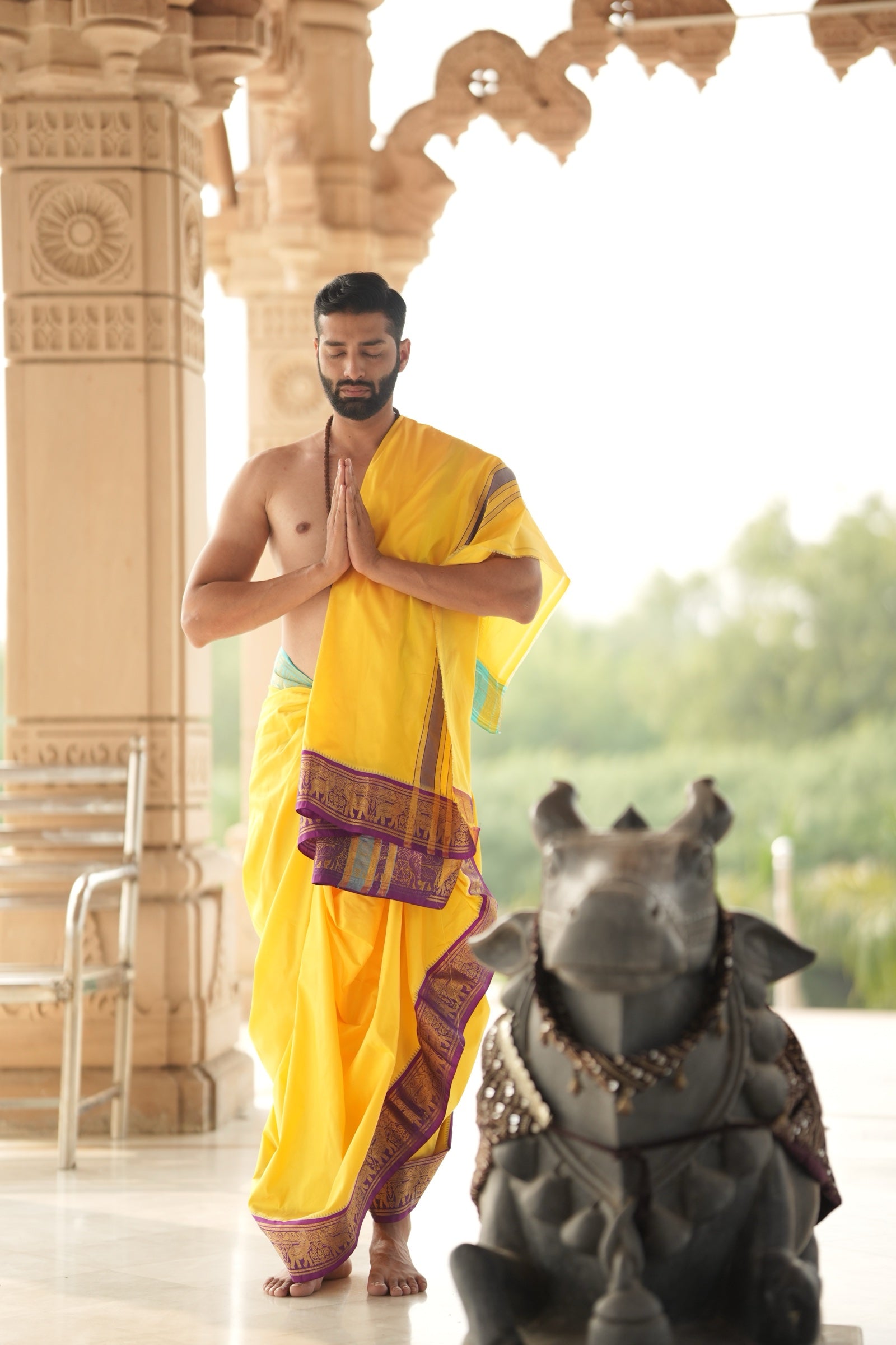Man wearing a luxurious koral golden jacquard border yellow pure silk dhoti with angavastram 