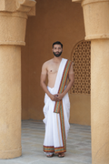 Man wearing a maroon green gold woven border cotton dhoti with uparana