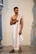Man wearing a orange color floral design white cotton dhoti with uparana