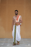 Man wearing a orange panel & green gold peacock zari border dhoti with matching uparana